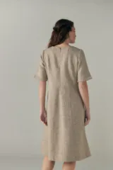 Vestido a la rodilla color beige, con escote en V, mangas cortas con detalle de tajo, bolsillos laterales y forro interior.