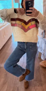 Sweater tejido en lana color crema con apliques de cuero bordados a mano en forma de chevron en tonos marrón, amarillo y rosa.