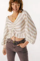 Blusa blanca de lino con escote en V, mangas largas abullonadas y frunce central.
