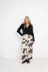 Pantalón cargo de denim rígido con estampado de vaca en blanco y negro, tiro alto, bolsillos frontales y traseros funcionales y hebillas metálicas regulables en la cintura.