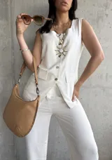 Chaleco color crema de lino con escote cuadrado, sin mangas, con cierre frontal de botones, dos bolsillos de parche y corte irregular en el ruedo.