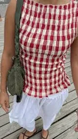 Top sin mangas con cuello redondo y diseño ajustado con frunces elásticos a cuadros rojos y blancos.