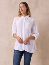 Camisa blanca de lino con cuello con solapa, manga larga regulable con presilla y botón, y bolsillo en el pecho.