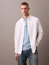 Camisa blanca de manga larga, confeccionada en tejido Oxford de algodón y elastano. Tiene cuello abotonado, cierre frontal con botones y logo de Calvin Klein bordado en el pecho. Corte regular.