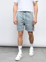 Bermuda gris de felpa sin friza, con cintura elástica ajustable con cordón y logo Umbro estampado en rojo en la pierna izquierda.