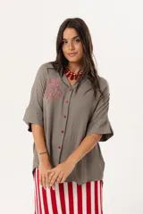 Camisa verde de silueta oversize con cuello camisero y manga 3/4. Tiene bordados de coral y caracol en el frente y botones a tono.