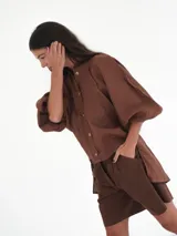 Camisa verde agua de lino, con botones de guampa, más larga atrás que adelante y espalda con tajo en el medio.