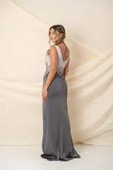 Vestido largo de fiesta, confeccionado en crepé de seda combinado en gris grafito y color nude. Presenta corsé con aplique bordado en hilo de seda con detalle de brillo en la cintura y falda con abertura lateral.