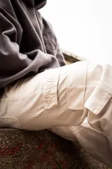 Pantalón cargo color beige, corte holgado, con bolsillos laterales y detalle de bordado en la solapa de uno de los bolsillos.