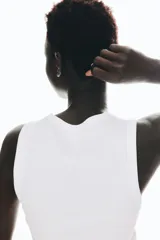 Musculosa blanca de punto acanalado de algodón, corte ajustado, con cuello redondo y sisas ribeteadas.