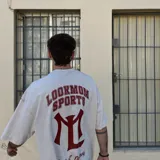 Camiseta oversize color crema con efecto acid wash, de alto gramaje (240 grs). Estampado trasero en serigrafía unicolor bordó con la inscripción "LOOKMOM SPORTS" y un logo con la letra "L".