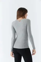 Remera gris de punto canalé, con escote redondo y mangas largas.