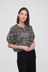 Blusa con estampado animal print en blanco y negro, de mangas cortas abullonadas y cuello redondo.