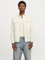 Camisa de algodón orgánico color crema, de manga larga, con cuello clásico, corte recto, cierre frontal con botones y dos bolsillos de parche en el pecho.