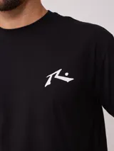 Remera blanca de hombre con logo de la marca Rusty estampado en el pecho y diseño a cuadros en la parte inferior trasera.