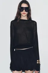 Falda pantalón corta negra de tiro medio, con cintura elastizada y detalle de tejido con volumen y pliegues. Cierre lateral con cremallera oculta.