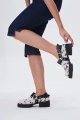 Zuecos de cuero con estampado animal print blanco y negro, con plataforma y hebillas metálicas.
