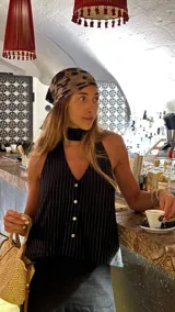 Blusa negra con rayas verticales plateadas, escote halter con abotonadura frontal y choker atado en la espalda.