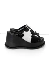 Sandalias con plataforma de cuero sintético color negro y estampado animal print de vaca en la tira delantera.