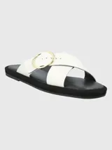 Sandalias de cuero sintético color blanco, con dos tiras anchas cruzadas sobre el empeine y hebilla circular dorada. Plataforma plana color negro.