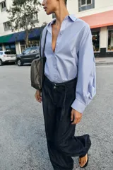 Jeans de tiro alto con corte bootcut, confeccionados en denim azul oscuro. Presentan costuras verticales decorativas en el frente, bolsillos laterales y cinturón del mismo tejido con hebilla metálica.