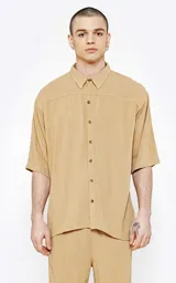 Camisa beige de lino con mangas 3/4, corte oversize y cuello clásico.
