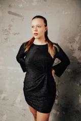 Vestido negro de punto con brillo, corte ajustado y mangas largas acampanadas.