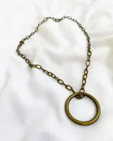 Collar de metal con eslabones y un anillo en el centro, de diseño minimalista.