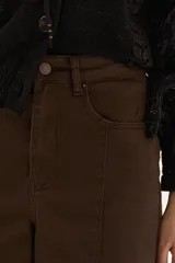 Jean de tiro alto y pierna ancha (wide leg) color marrón oscuro, con costuras visibles en el frente.