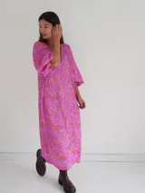 Vestido midi de corte holgado con estampado floral en tonos rosa y naranja, escote en V y mangas cortas amplias.