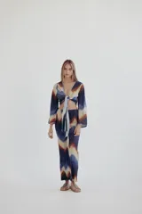 Top corto con estampado psicodélico en tonos azules, marrones y beige. Tiene escote en V pronunciado y mangas largas acampanadas. Se ata en el centro del busto.