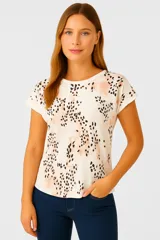 Remera blanca con estampado de manchas negras y rosadas, de corte holgado y manga corta.
