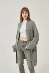 Saco largo de tejido de punto grueso color gris, con mangas largas y bolsillos frontales. Diseño holgado y sin cierre.