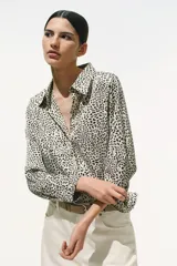 Camisa entallada de manga larga en tejido elástico de satén con estampado de leopardo. Modelo con cuello abierto, botonadura frontal y puños abotonados con abertura. Pinzas adelante y atrás para estilizar la figura.