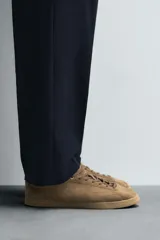 Zapatillas de cordones color marrón claro, con capellada de cuero serraje, puntera redonda y suela plana a tono.