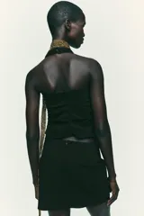 Falda pantalón negra de tiro alto con delantero cruzado y pliegues. Cierre trasero con cremallera oculta.