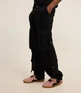 Pantalón cargo recto color negro, de sarga de algodón, con bolsillos laterales con hebillas y trabillas en la cintura.