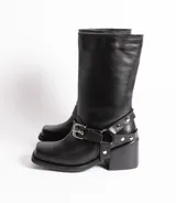 Bota de cuero color marrón oscuro, de caña media, con hebilla y tachas decorativas.