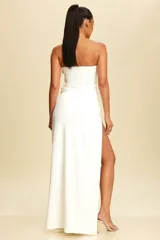 Vestido largo blanco strapless con abertura alta en la pierna y detalle de pedrería en el escote y en la abertura.