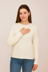 Sweater de tejido punto color blanco roto, de manga larga y cuello redondo, con calce holgado.