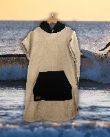 Poncho de toalla beige con capucha forrada en negro y bolsillo canguro negro.