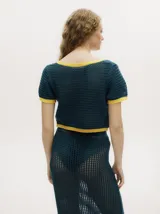 Top tejido calado color azul petróleo con cuello en V y botones carey. Tiene mangas cortas y puños en color amarillo contrastante.