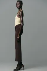 Falda midi marrón chocolate de tiro alto, confeccionada en poliamida con cintura elástica, detalle de frunces y caracola metálica dorada en el delantero.