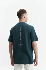 Remera azul petróleo de manga corta con textura waffle y estampado con la frase "Less perfection - More authenticity MISTRAL" en la espalda.