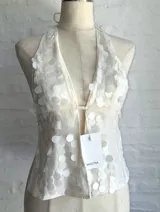 Top halter color beige claro, ajustado al cuerpo, con escote pronunciado en V y cubierto de lentejuelas redondas. Se ajusta mediante tiras en el cuello y la espalda.