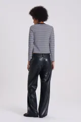 Pantalón recto de cuero sintético negro, estilo jeanero con tiro bajo, bolsillos delanteros y traseros, pretina con botón y pasacintos.