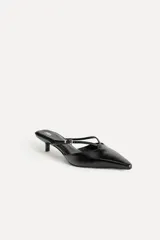 Zapato destalonado tipo mule de cuero negro, con punta fina, tira delantera con hebilla y tacón kitten.