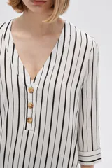 Camisa holgada de viscosa con estampado de rayas verticales en blanco y negro, cuello en V y mangas 3/4 con detalle de botones.