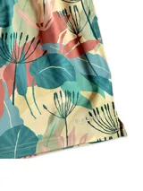 Short de baño blanco con estampado de hojas de palmera en tonos verde, rojo y amarillo.
