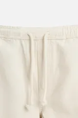 Bermuda color beige de denim de algodón, corte relaxed fit, con cintura elástica ajustable con cordón, bolsillos frontales y traseros.